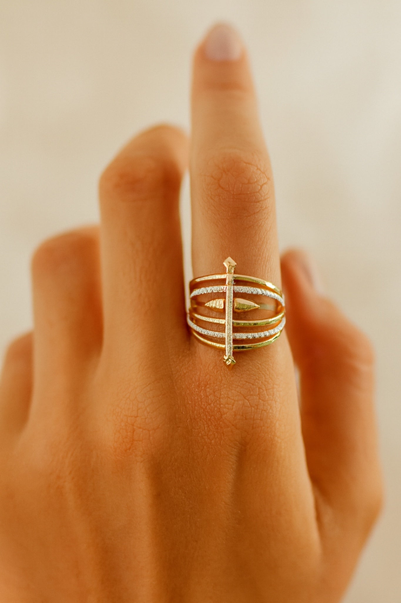 Gold ring on a finger against a neutral background