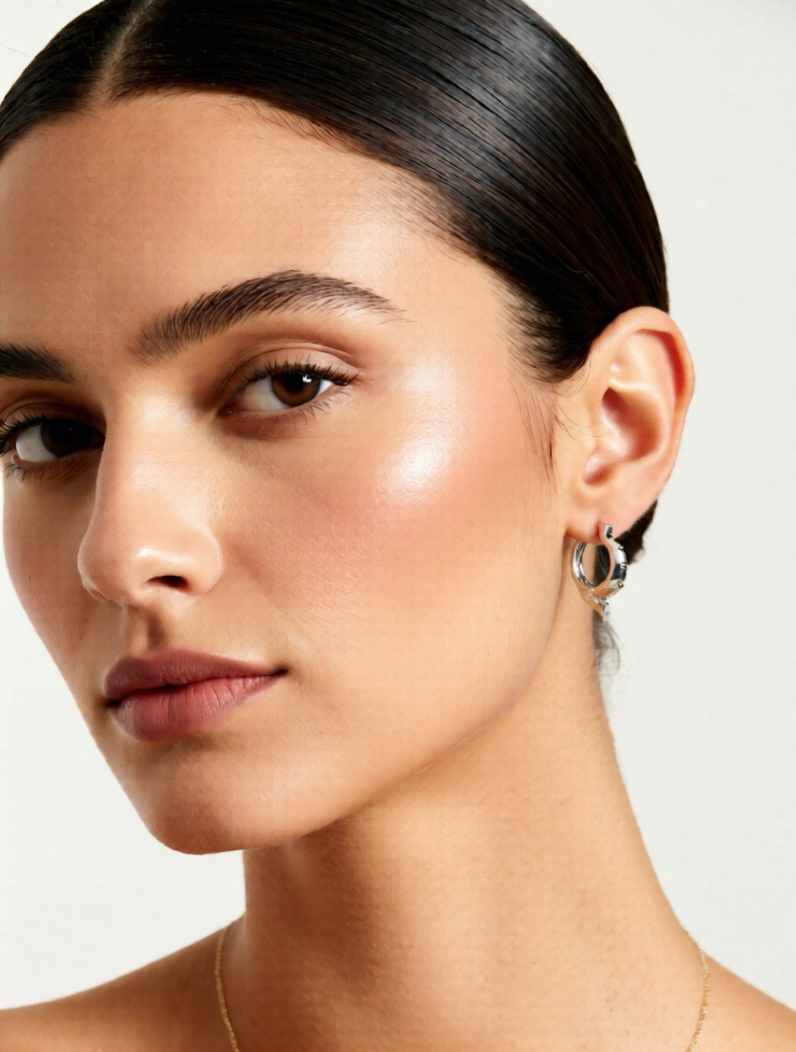 Close-up of a woman wearing earrings with a neutral background