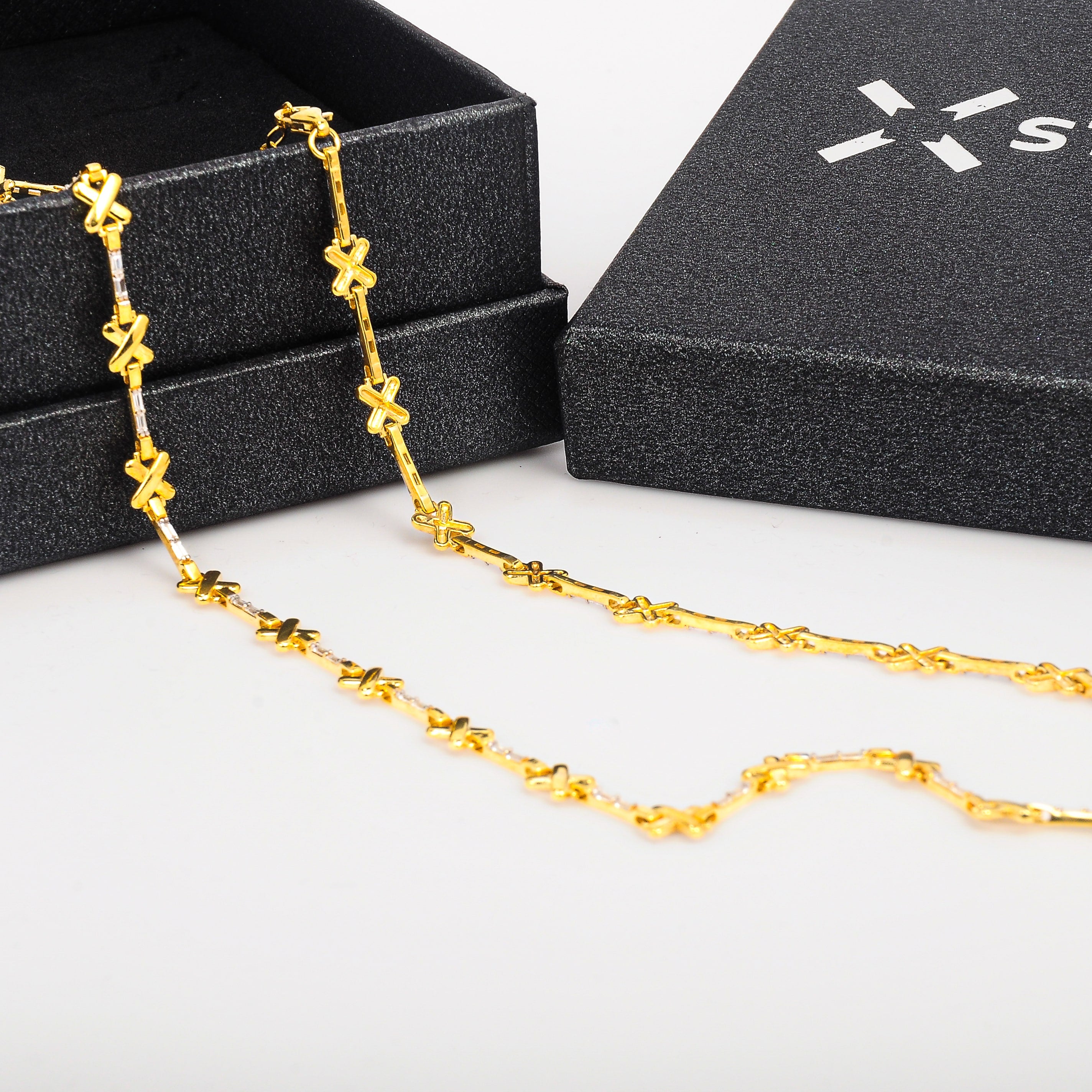 Gold necklace on a white surface with a black box in the background