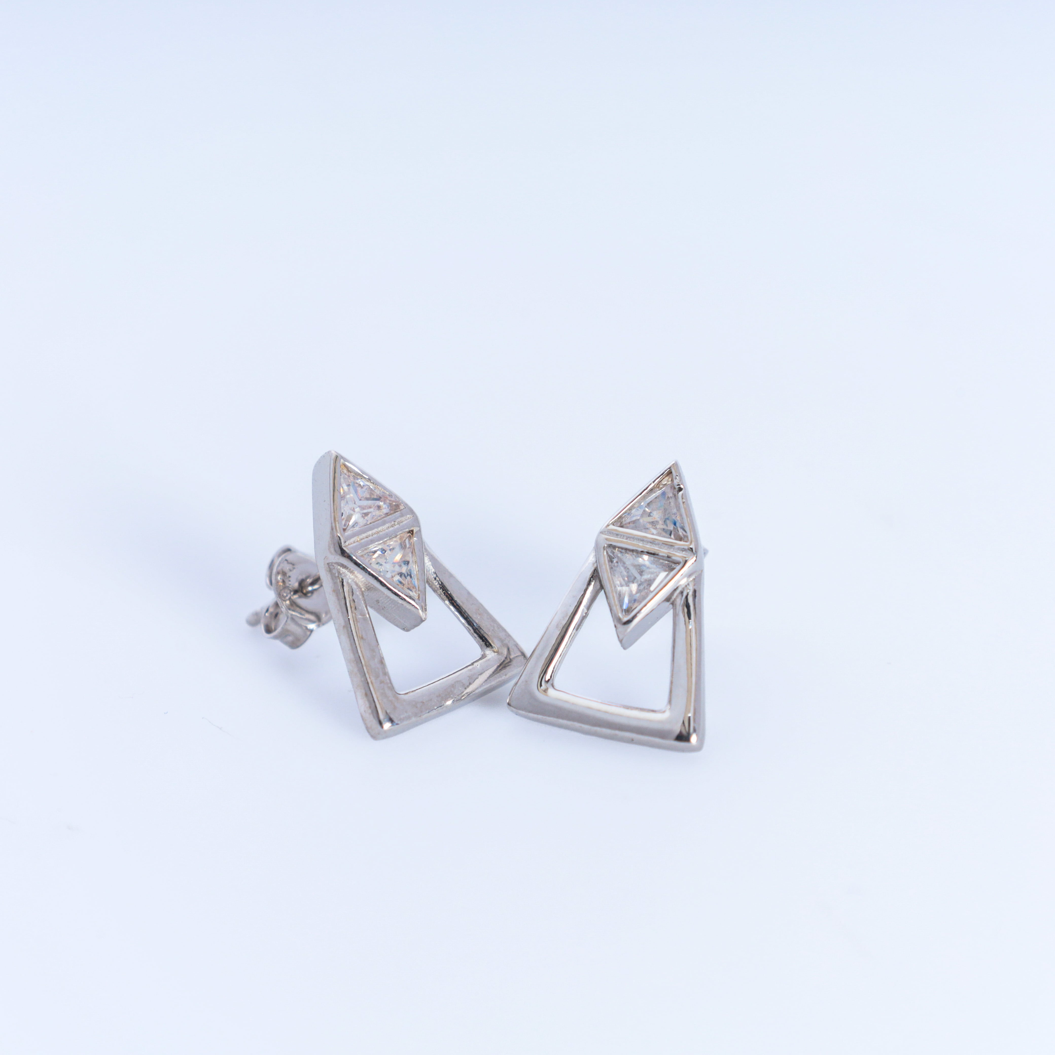 Pair of silver triangle-shaped earrings on a light gray background