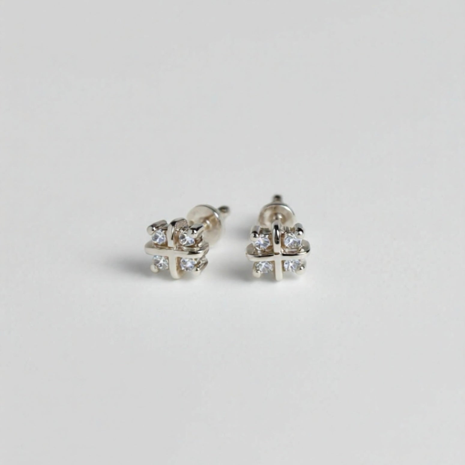 Pair of silver earrings with clear gemstones on a light gray background