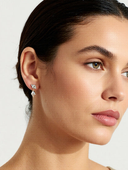 Close-up of a woman wearing diamond earrings with a neutral background