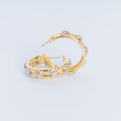 Pair of gold hoop earrings with star designs on a light gray background