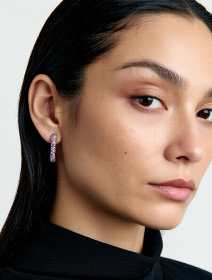 Close-up of a woman wearing pink hoop earrings with a plain background