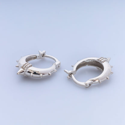 Silver hoop earrings with spike details on a light blue background