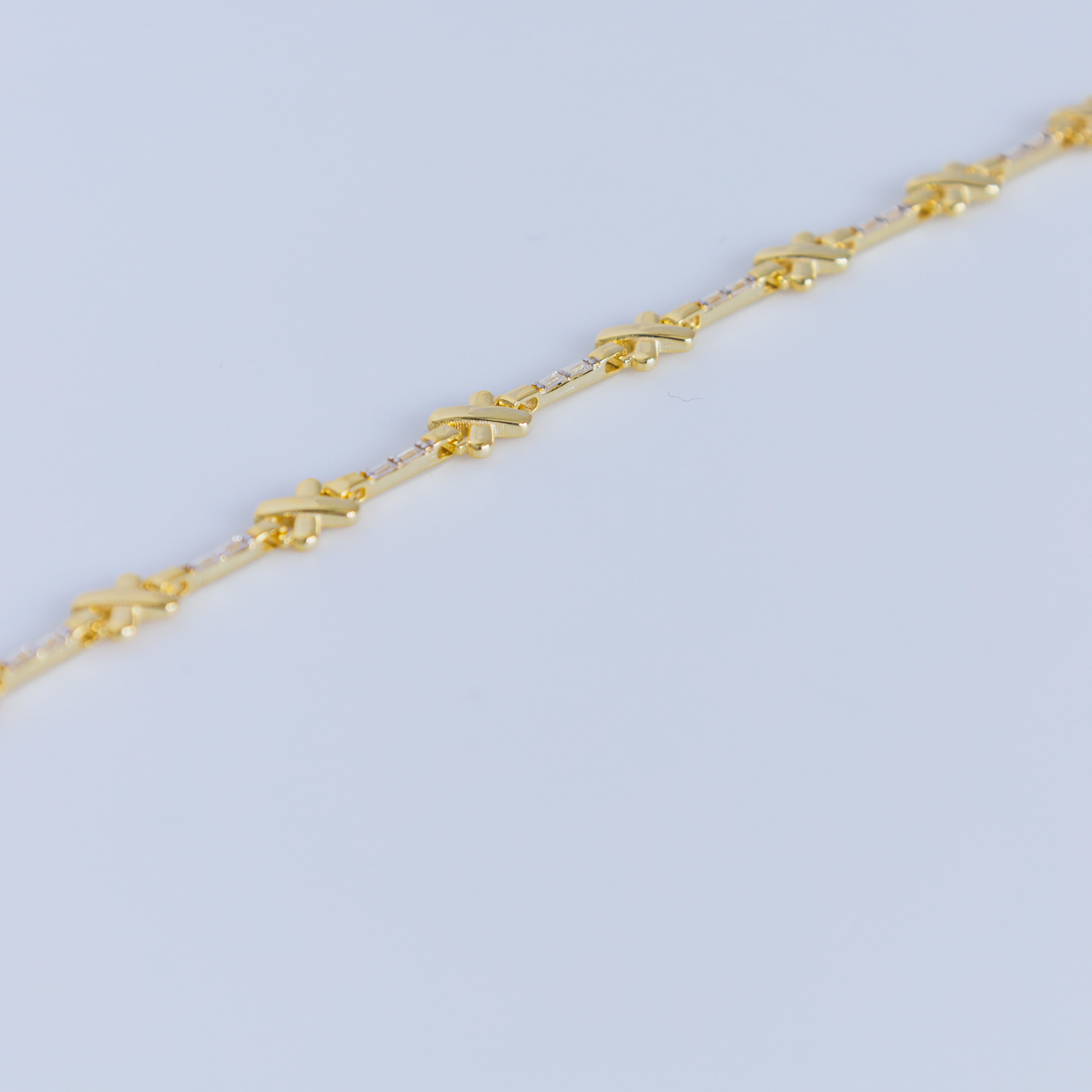 Gold bracelet in a black jewelry box with 'X Studio' branding on a light gray background