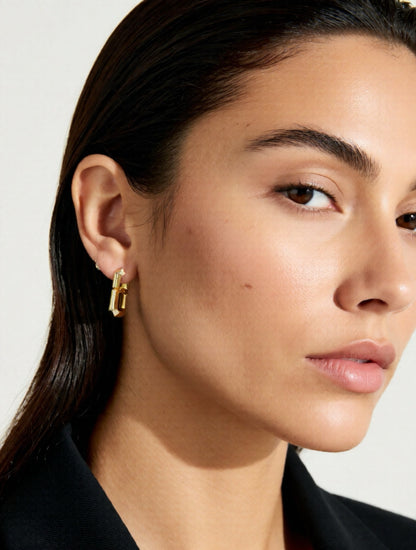 Close-up of a woman wearing gold earrings with a white background