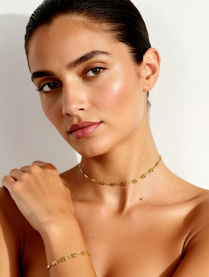Woman wearing a gold necklace and bracelet against a neutral background