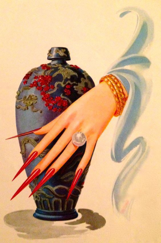 Decorative vase with floral patterns held by a hand with long red nails against a light background