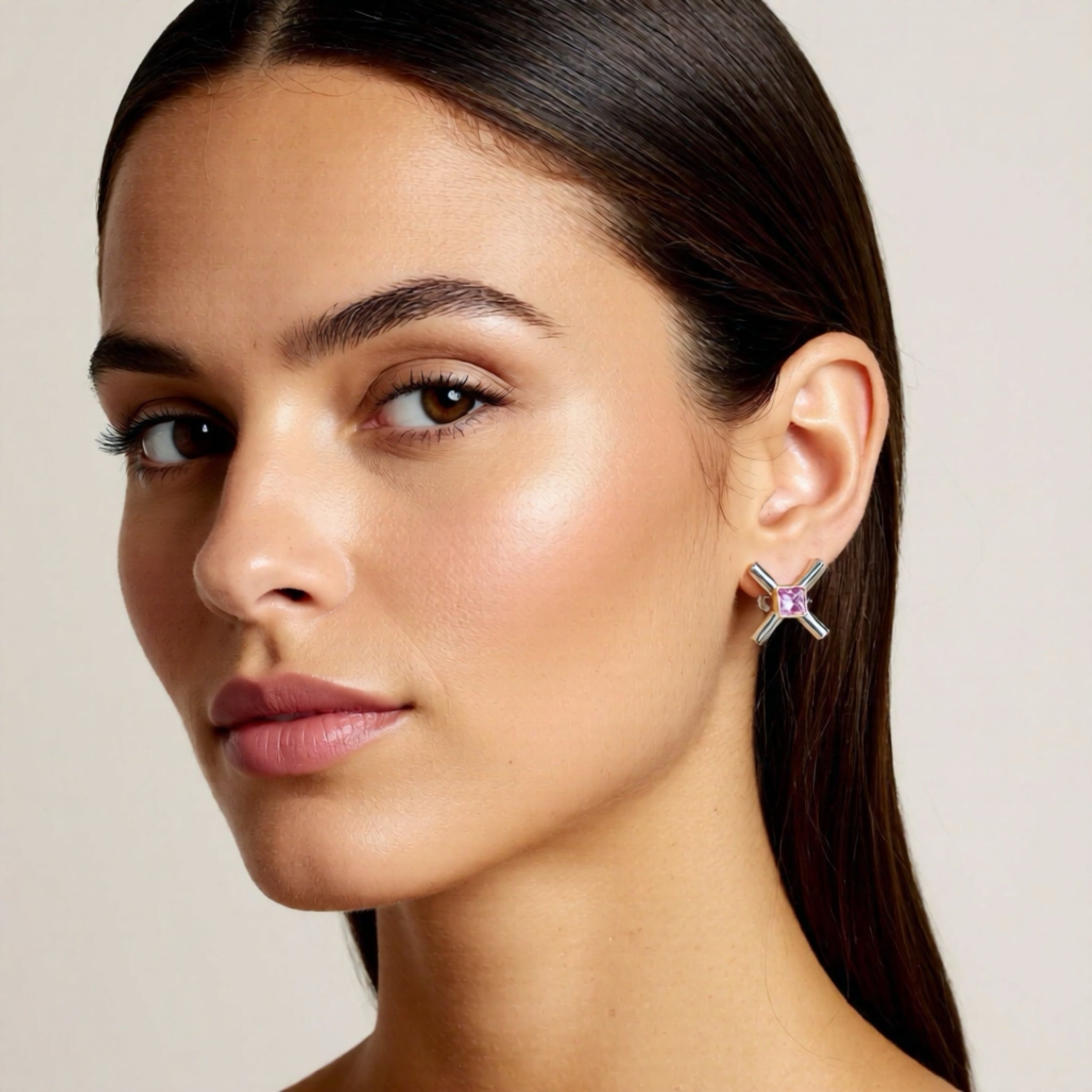 Close-up of a woman wearing a star-shaped earring with a purple gemstone on a neutral background