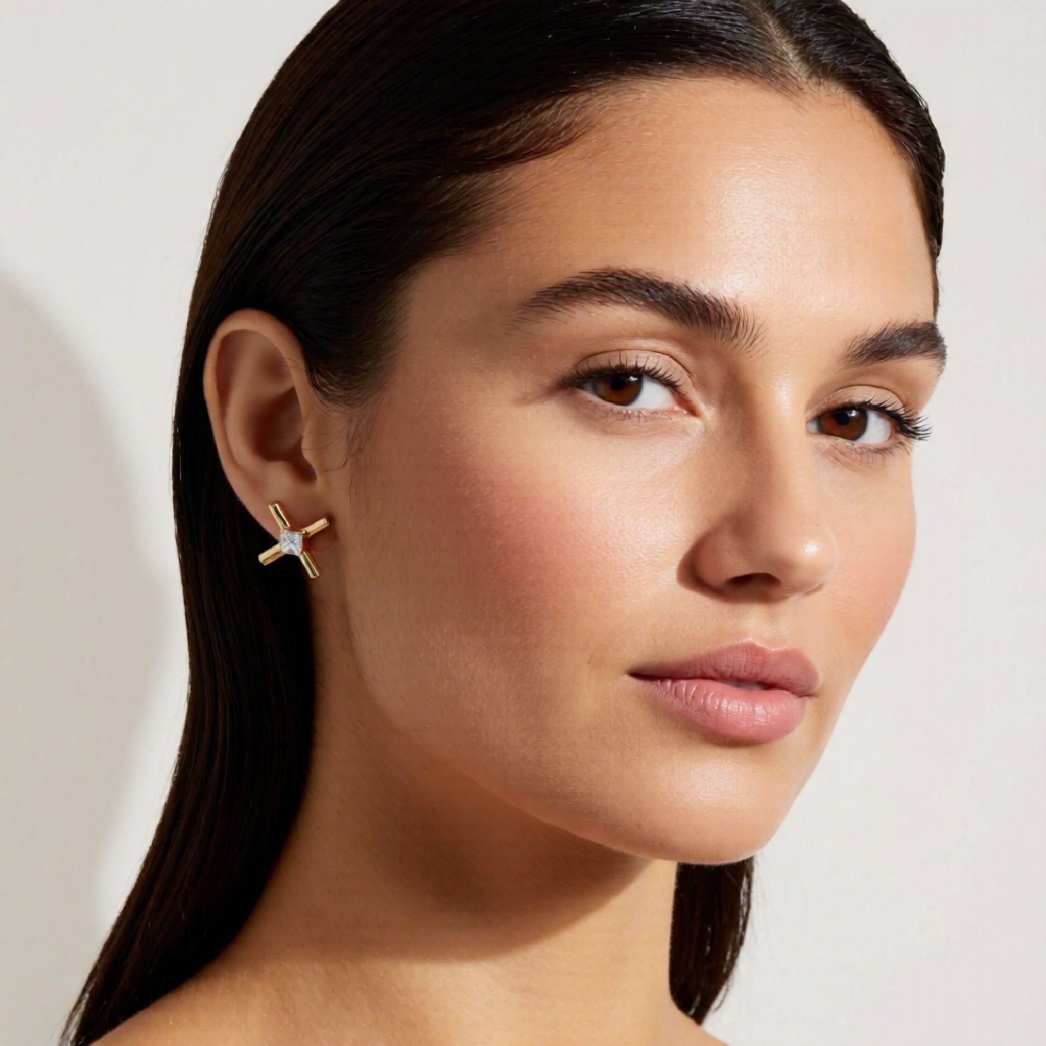 Close-up of a woman wearing a gold earring with a star design.