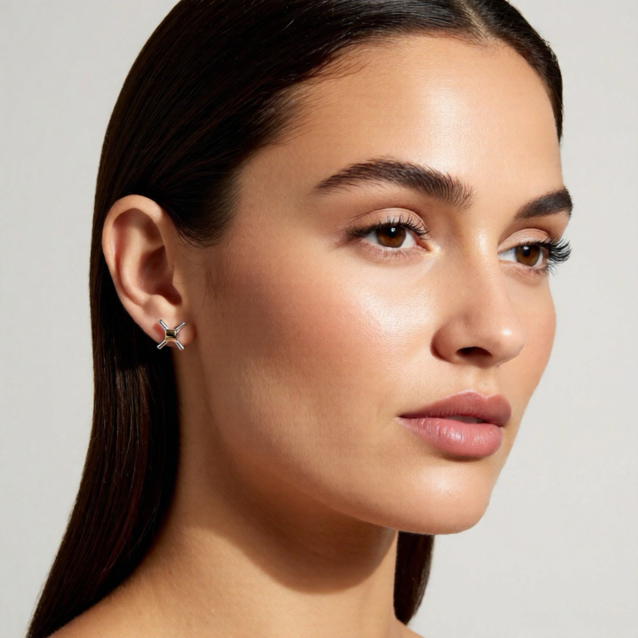 Close-up of a woman wearing a star-shaped earring against a neutral background
