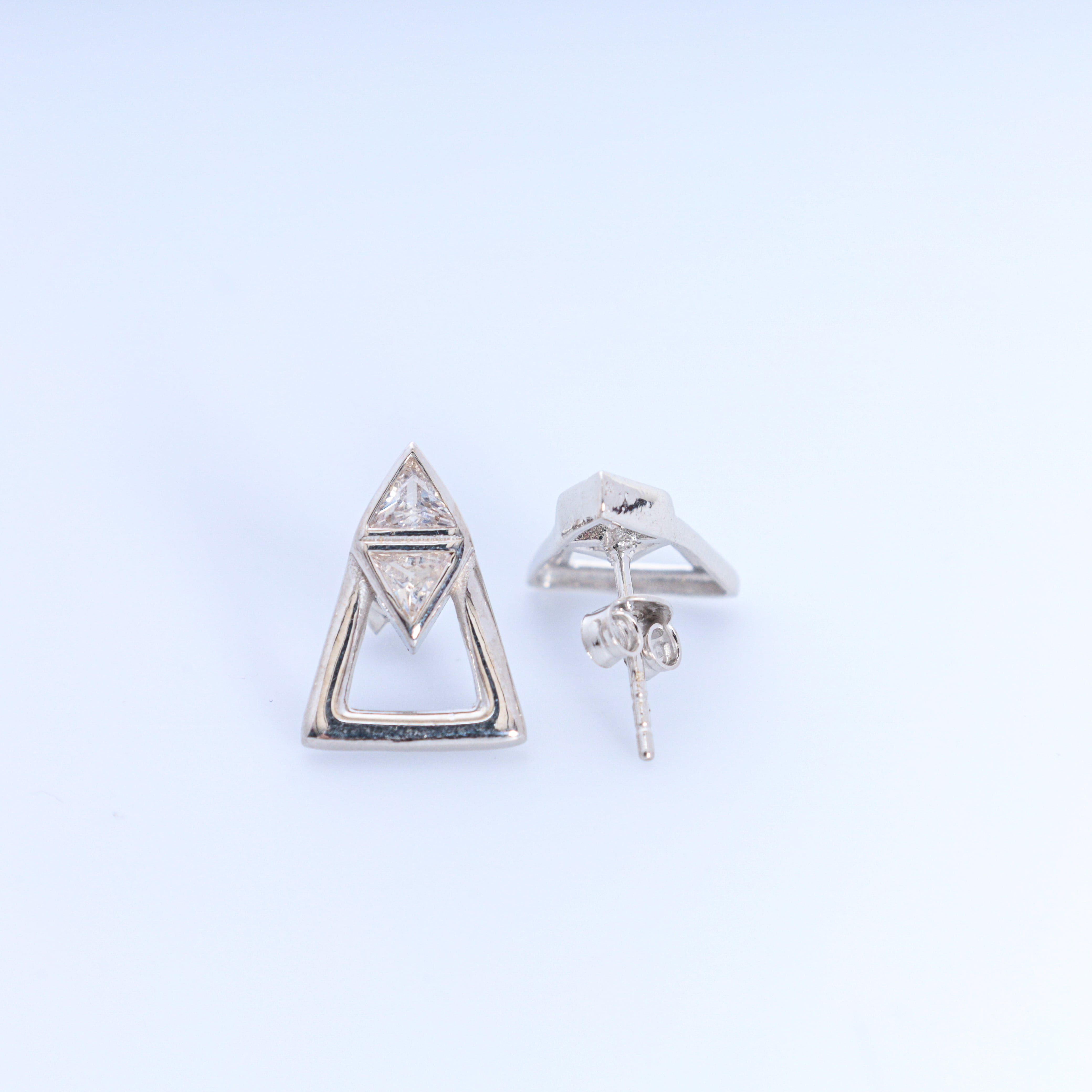Pair of silver triangle earrings on a light gray background