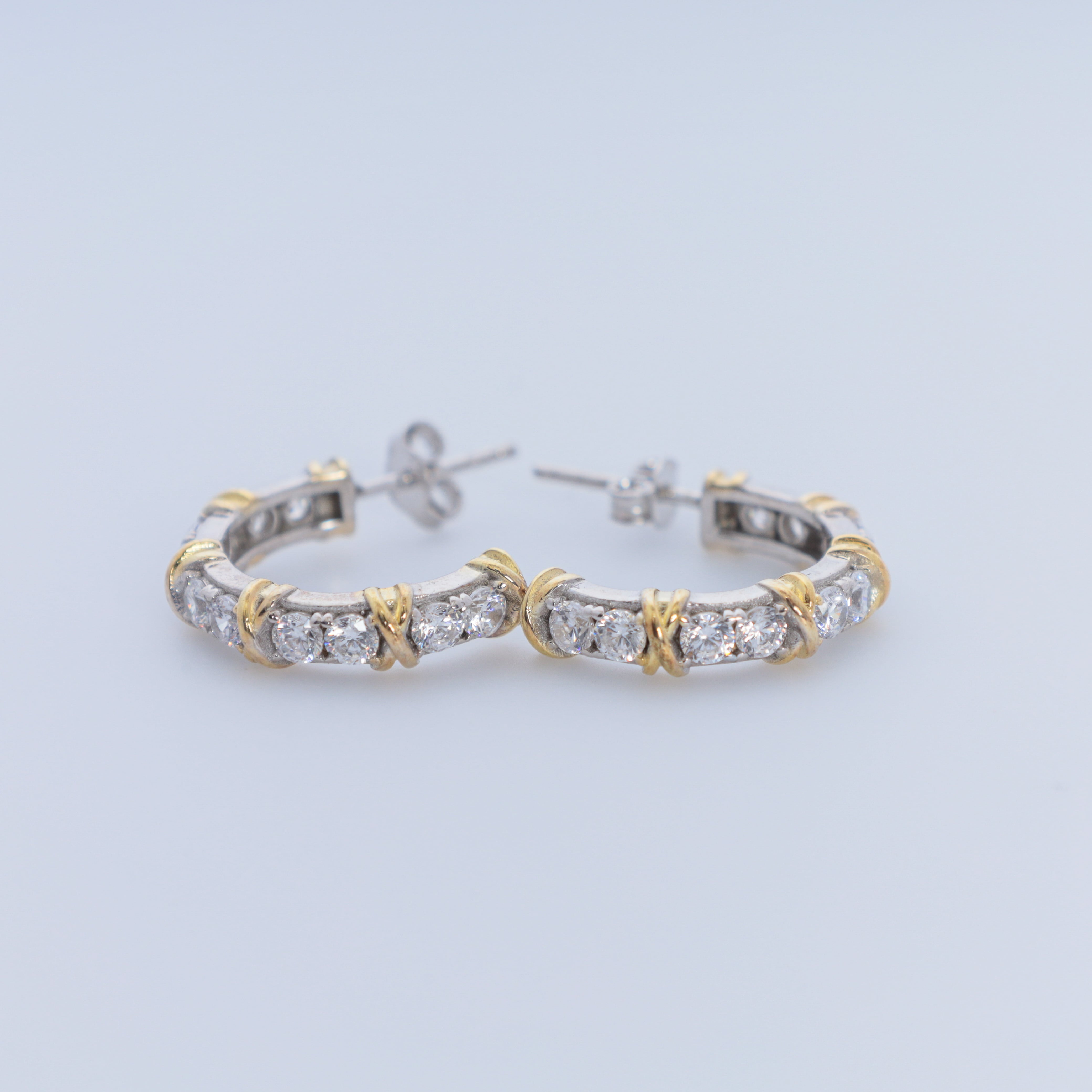 Pair of hoop earrings with gold and silver accents on a light gray background